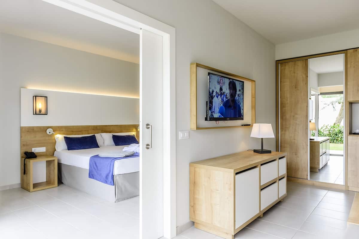 A modern hotel room with a bed, bedside table, and a wooden cabinet.