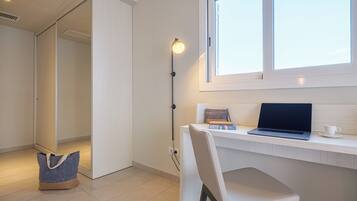 Ein modernes Zimmer mit Schreibtisch, Stuhl, Laptop und Fenster.