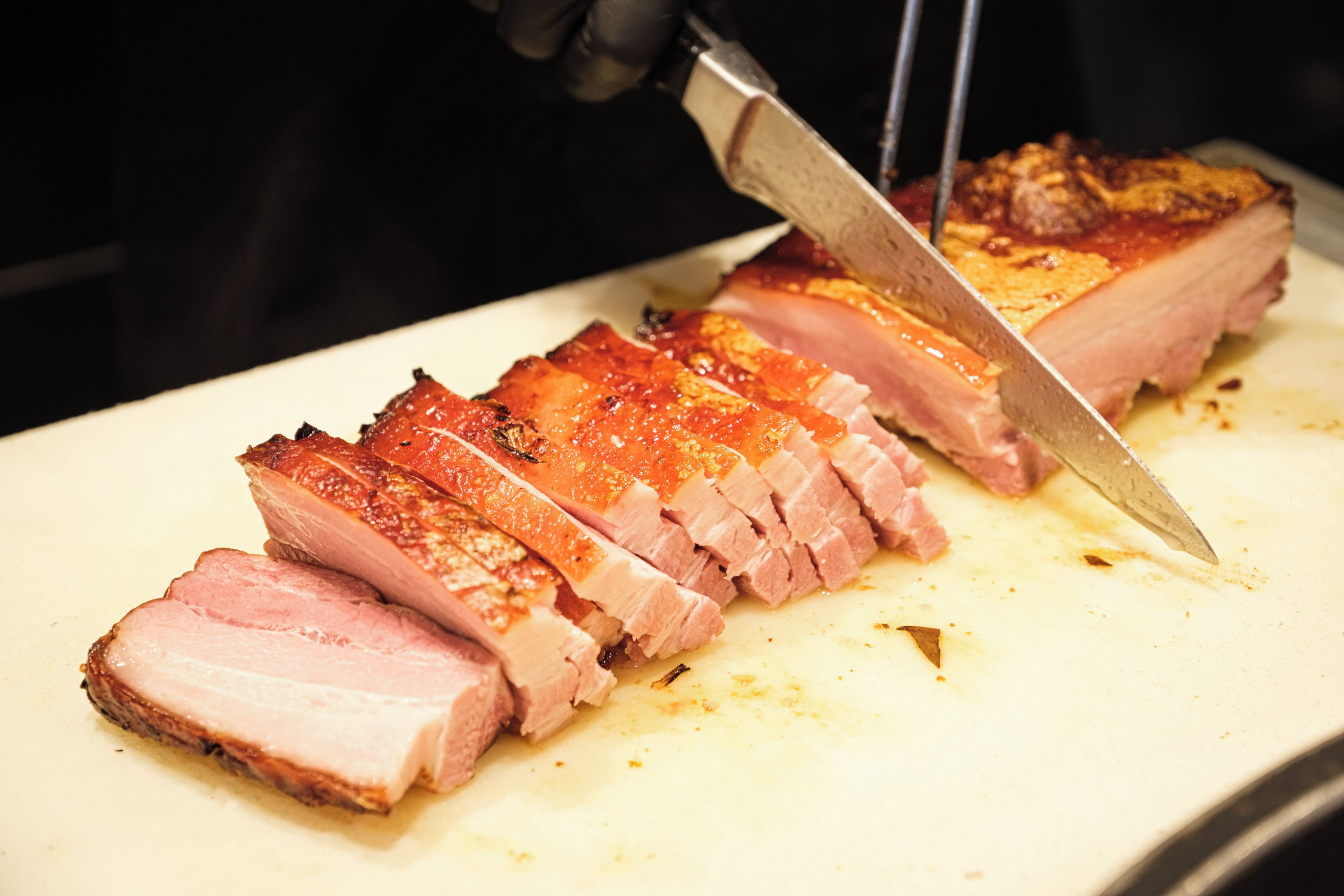 A close-up of a cooked meat dish being sliced with a knife.