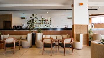 Een receptiebalie, een zithoek en een bar met verschillende flessen in de lobby.