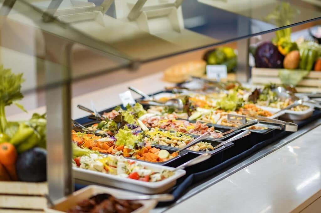 A buffet with various dishes including salads, vegetables, and meats.
