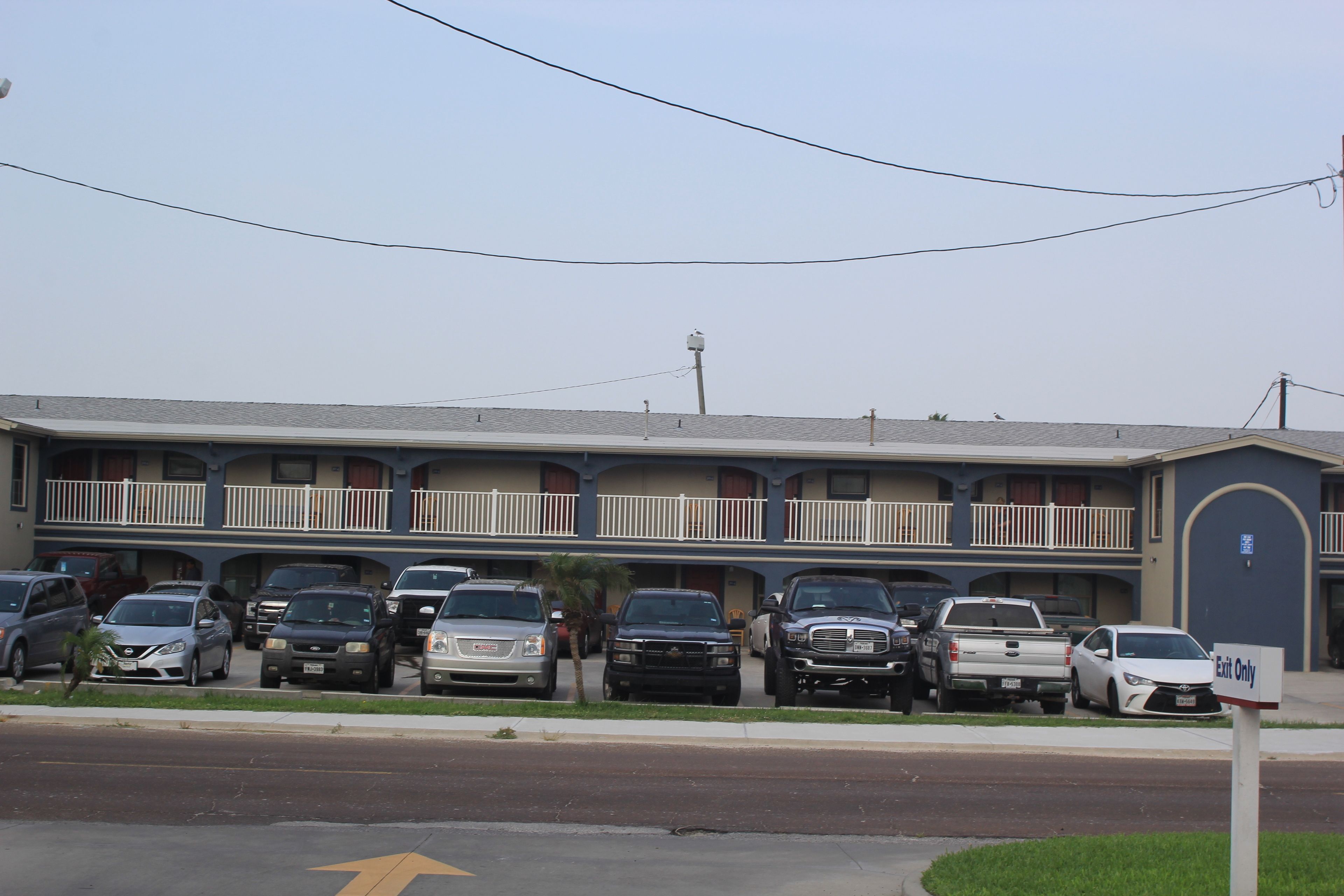 A motel with multiple parking spaces and a sign indicating 'Exit Only' on the street.