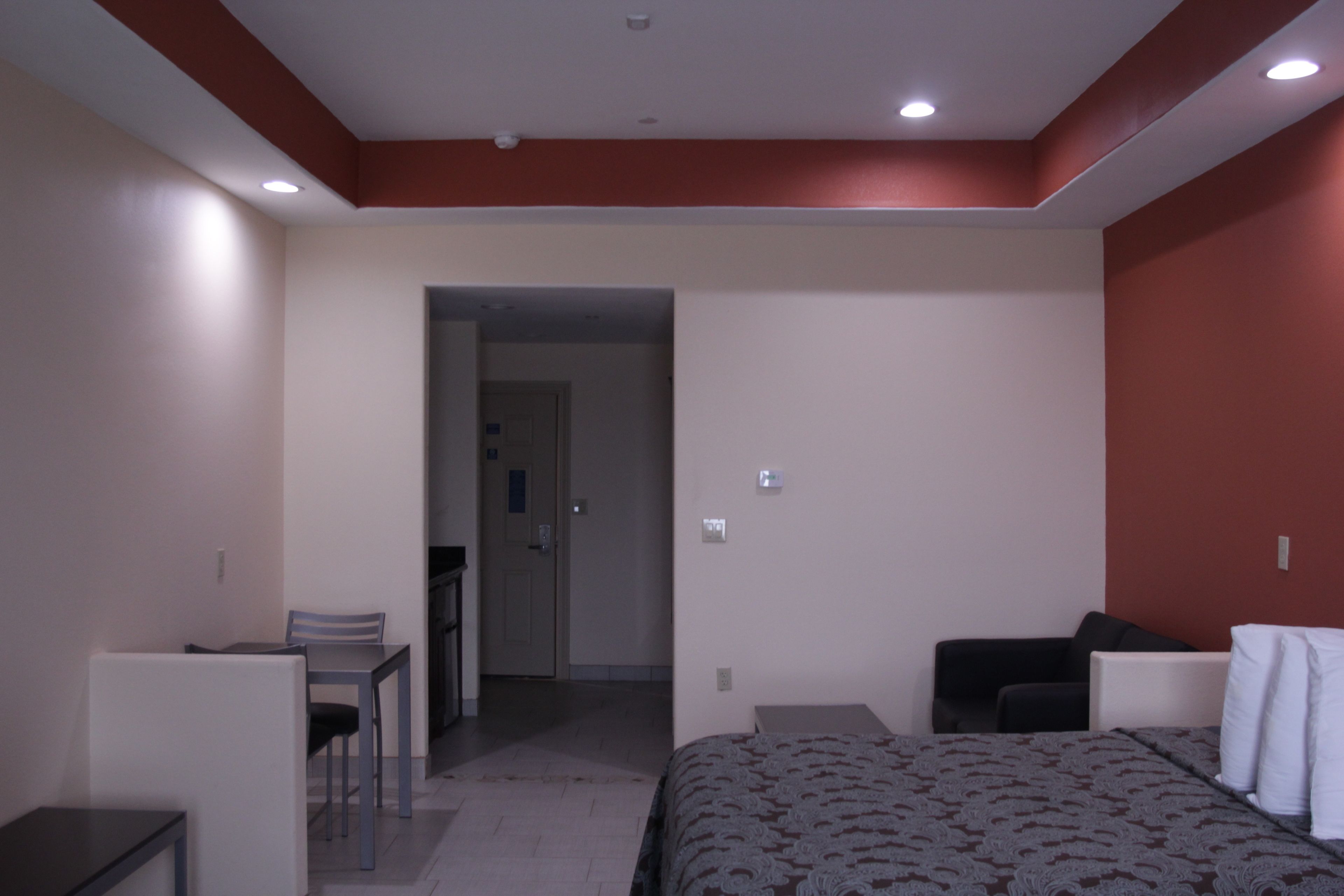 A hotel room with a bed, a desk, a chair, and a small table.