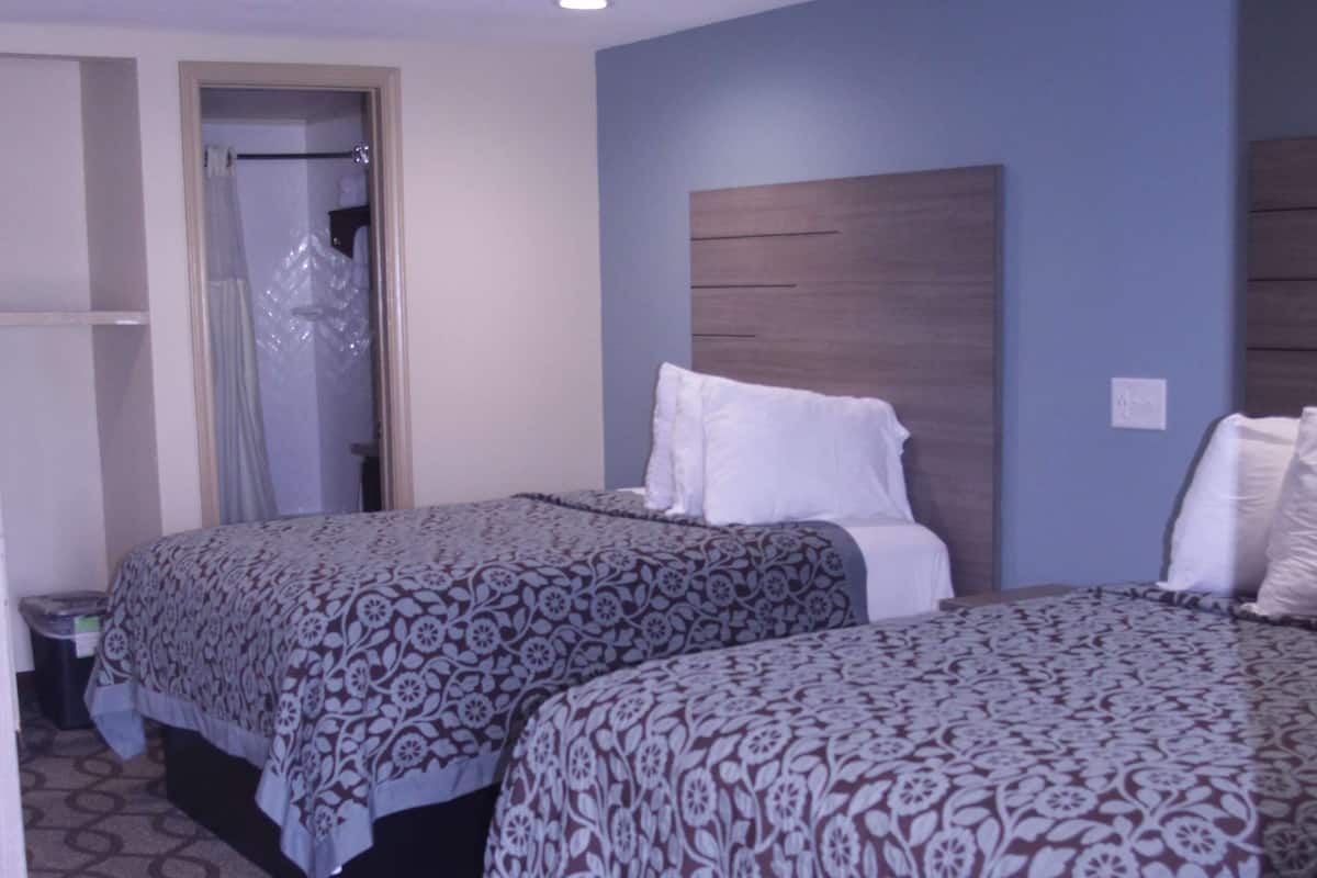 Une chambre d’hôtel avec deux lits, une armoire et une salle de bain.