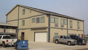 A multi-story building with a garage, a balcony, and a dumpster. - Americas Best Value Inn Port Aransas (Port Aransas)