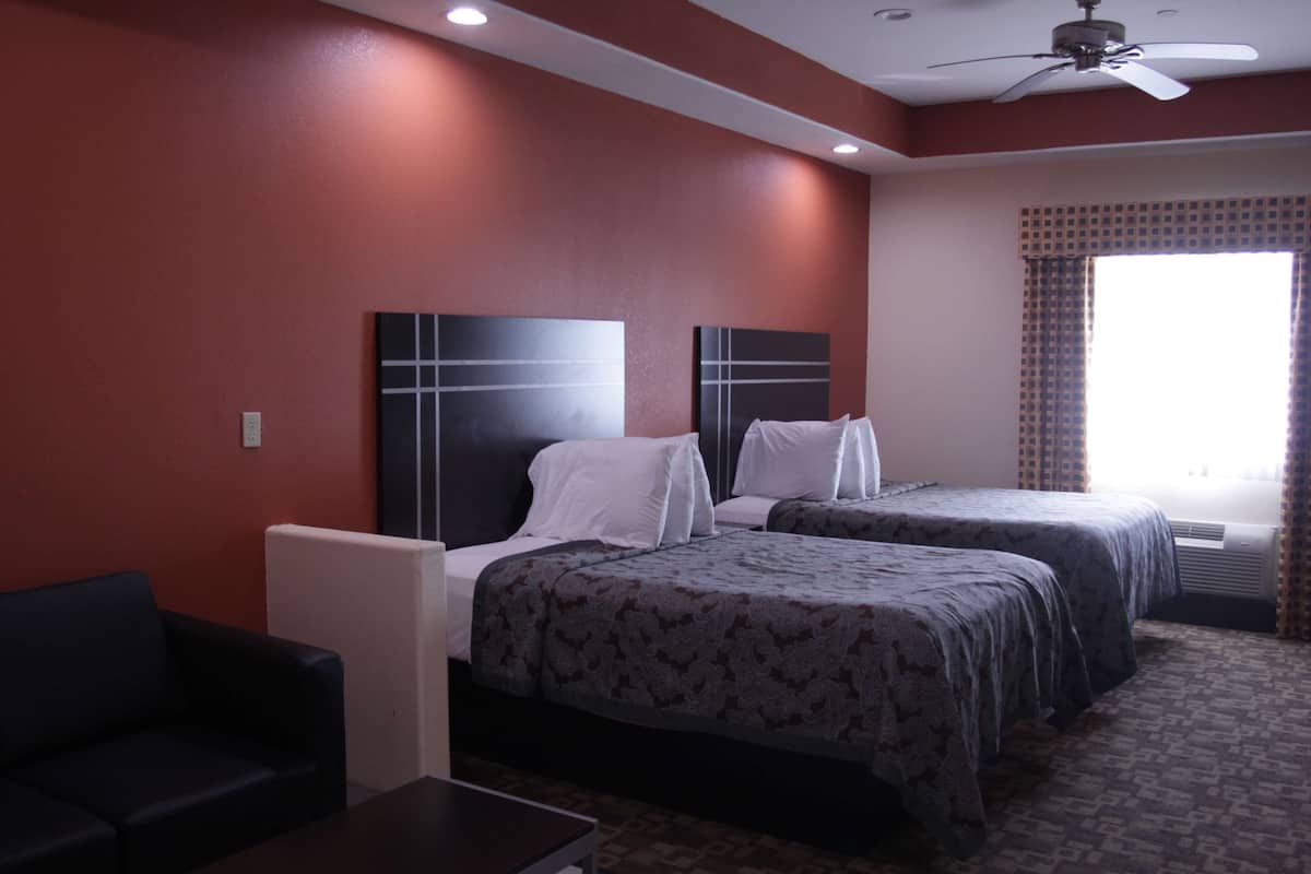 Une chambre d’hôtel avec deux lits, un ventilateur de plafond et une fenêtre avec des rideaux.