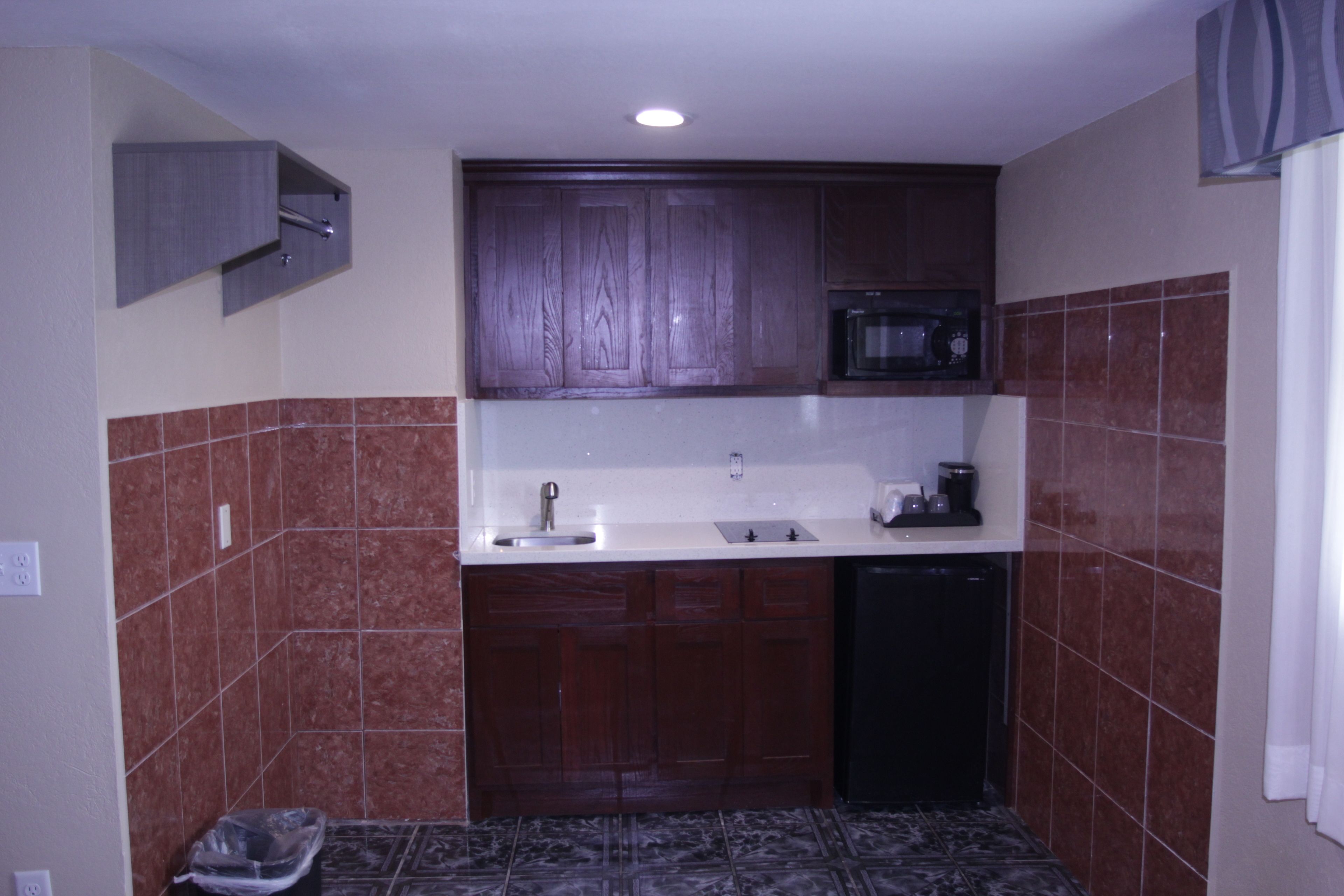 A compact kitchen with wooden cabinets, a microwave, and a dishwasher.