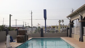 A rectangular pool with a stone accent wall and a metal railing. - Americas Best Value Inn Port Aransas (Port Aransas)