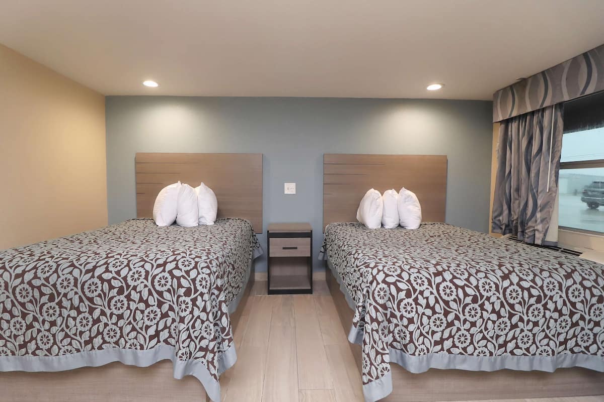 Une chambre d’hôtel avec deux lits, une table de chevet et une fenêtre avec des rideaux.