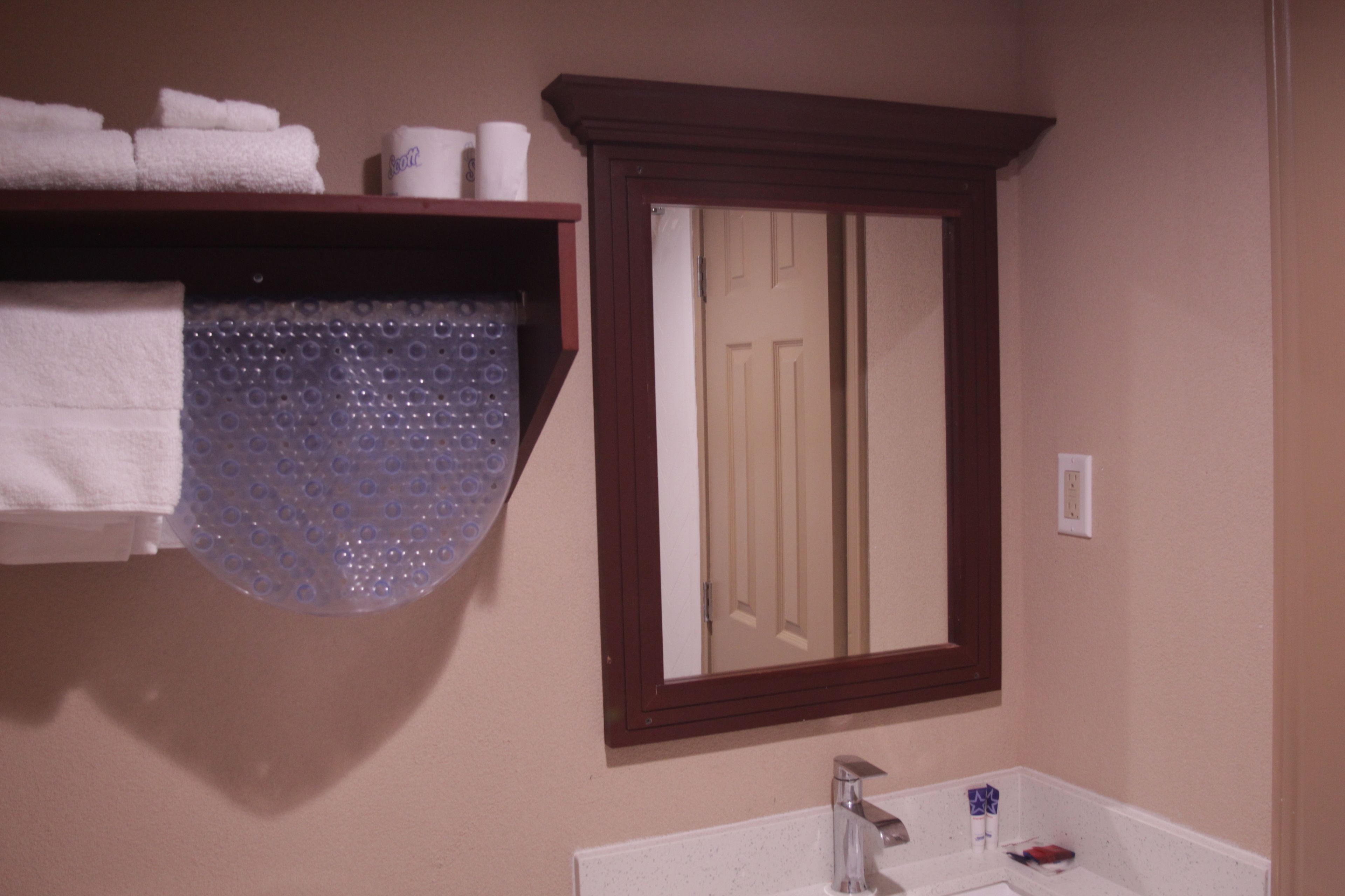 A bathroom with a wooden medicine cabinet, a mirror, and a sink.