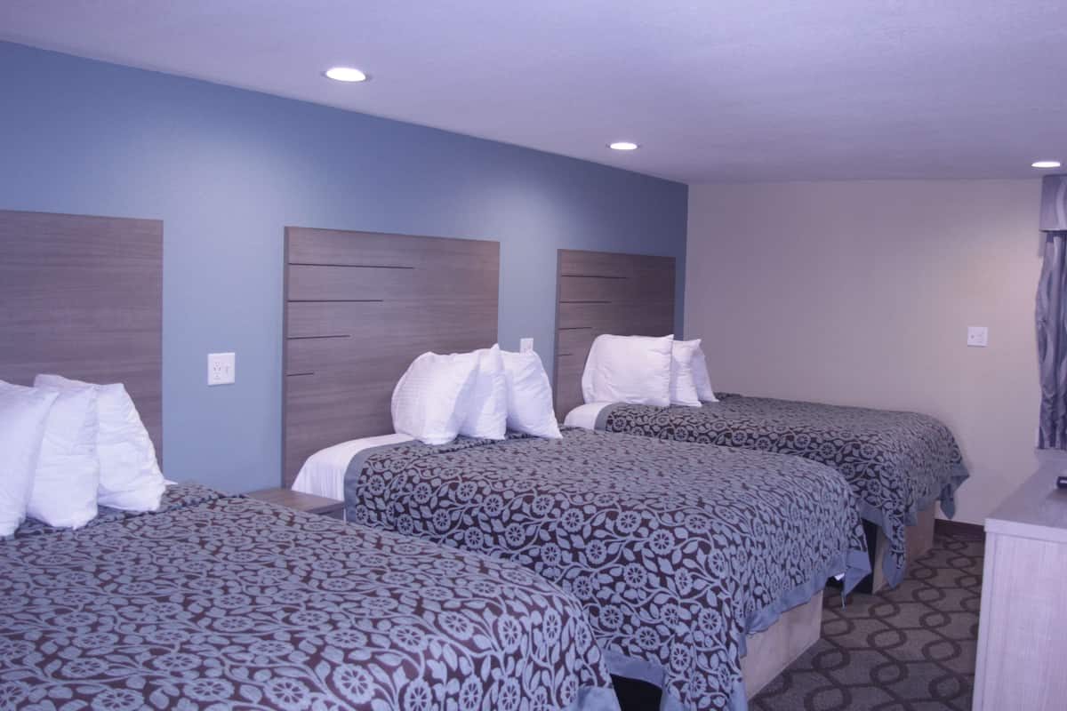 Une chambre d’hôtel avec deux lits, chacun doté d’une tête de lit et d’oreillers, ainsi qu’un petit bureau avec une chaise.