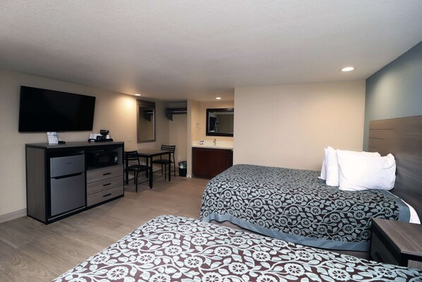 Habitación de hotel con cama, escritorio, televisor y kitchenette.