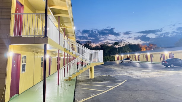 A motel with a two-story structure, a central staircase, and a parking area. - Royal Inn (Daytona Beach)