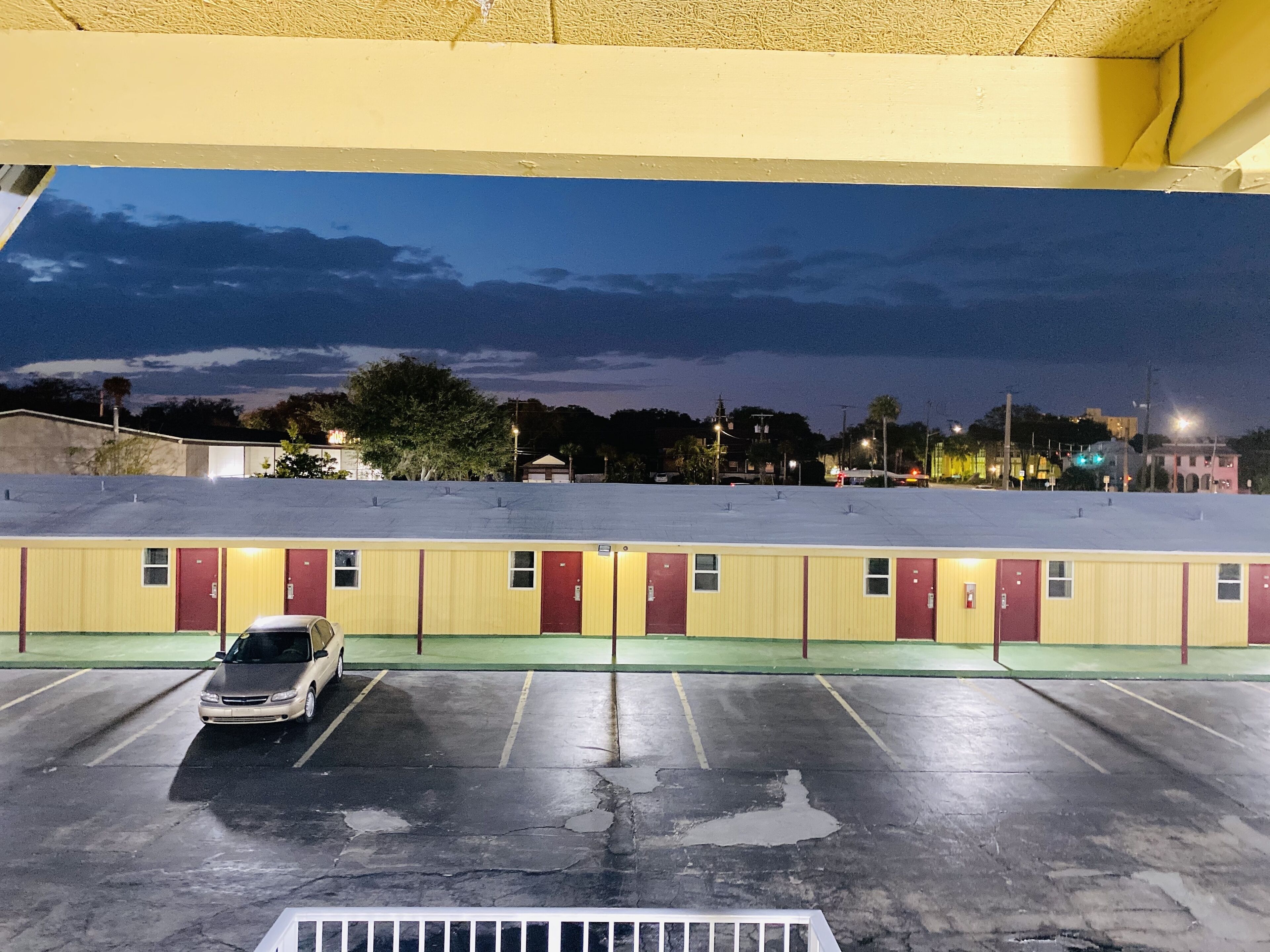 A motel with a parking lot and a car parked in front.