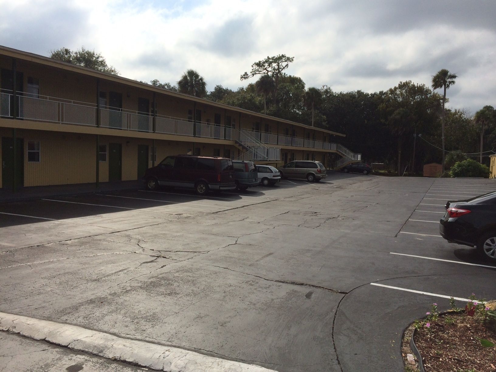 Un motel con una fila de espacios de estacionamiento y un edificio con balcón.