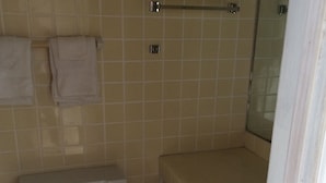 A bathroom with a toilet, a towel rack, a shower area, and a sink. - Royal Inn (Daytona Beach)