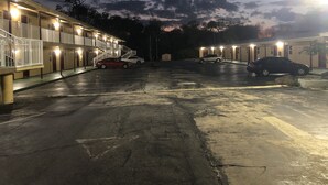 A motel with multiple rooms, a parking area, and a staircase leading to the upper floors. - Royal Inn (Daytona Beach)