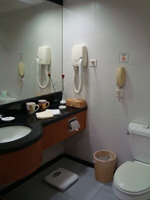 A bathroom with a sink, toilet, and two phones on the wall.