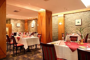 Un ristorante con tavoli apparecchiati, pareti in pietra e quadri appesi.