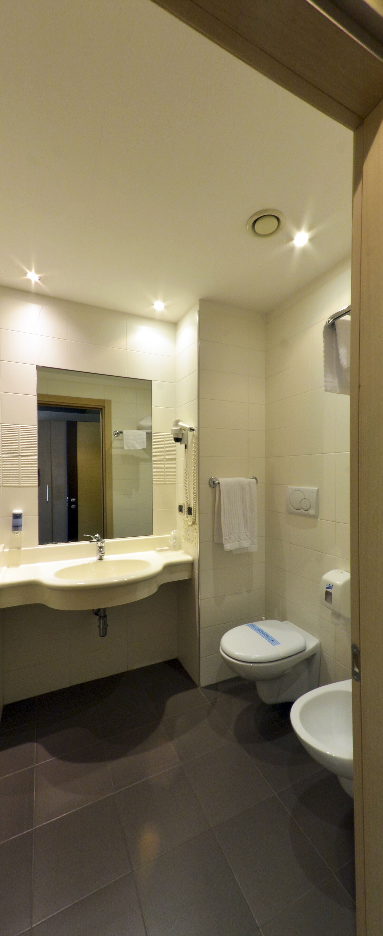 A modern bathroom with a sink, mirror, toilet, and bidet.