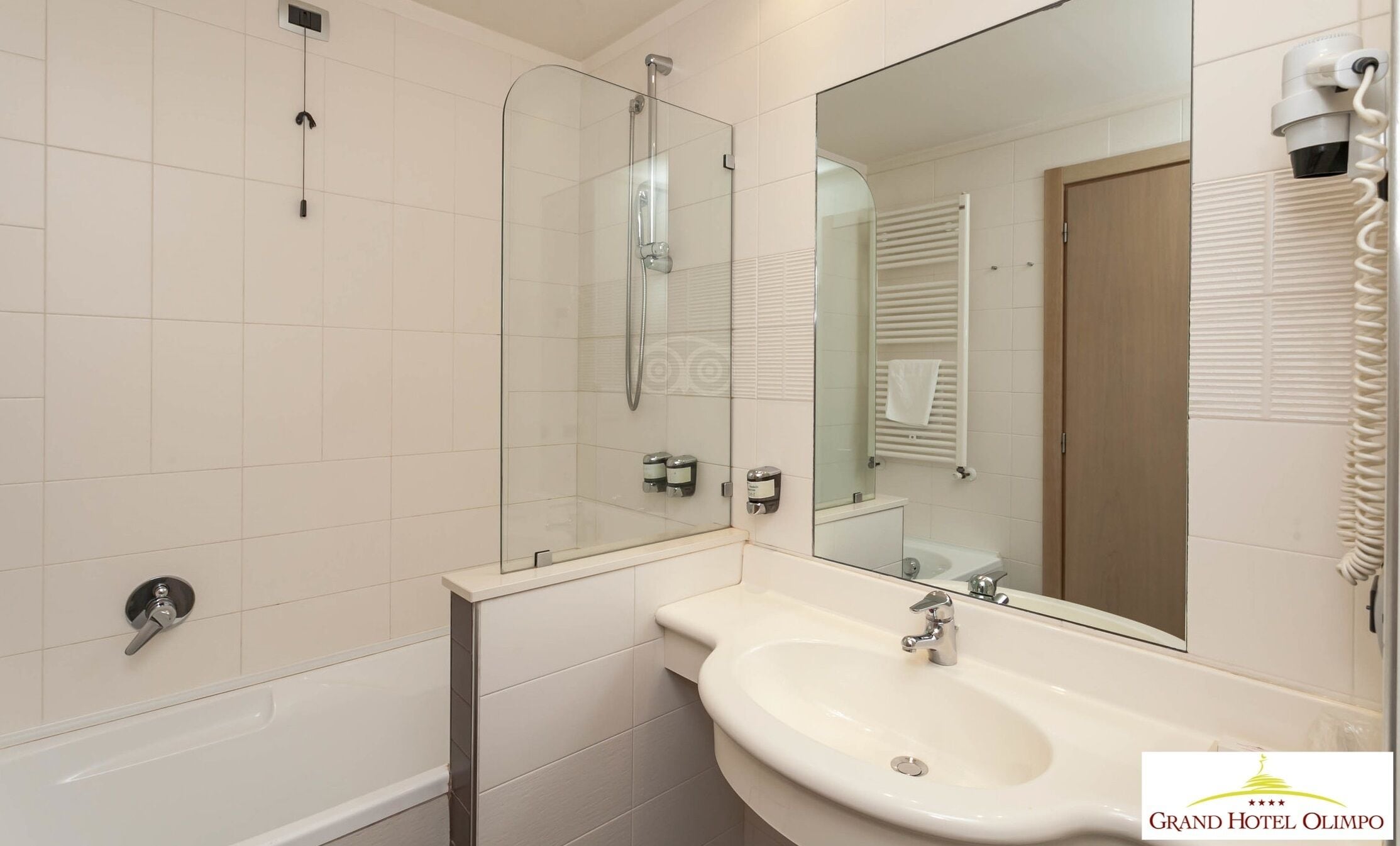 A bathroom with a glass-enclosed shower, a white sink, and a large mirror.