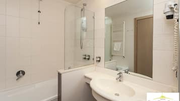 A bathroom with a glass-enclosed shower, a white sink, and a large mirror.