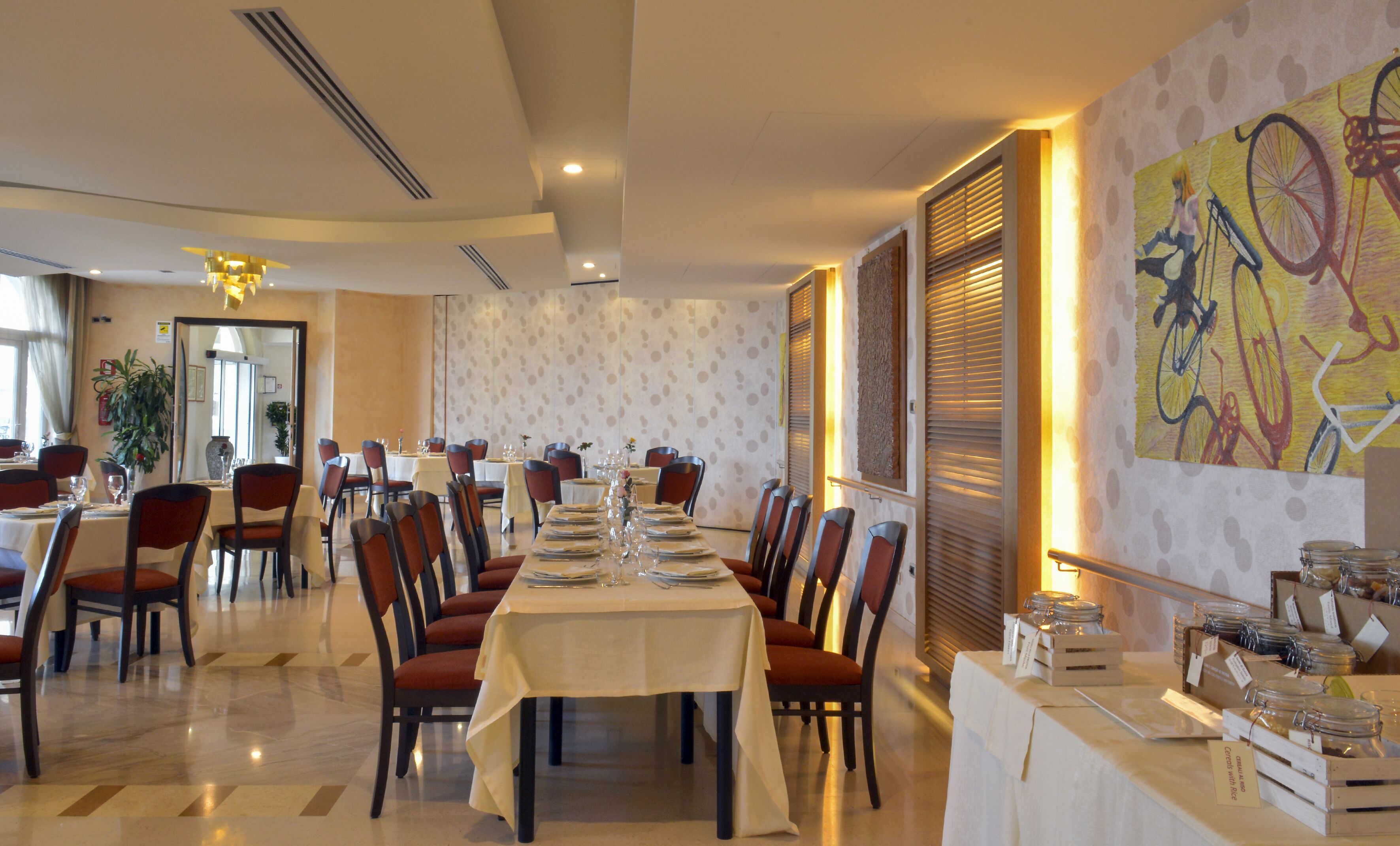A restaurant with a long dining table set for a meal, surrounded by chairs.
