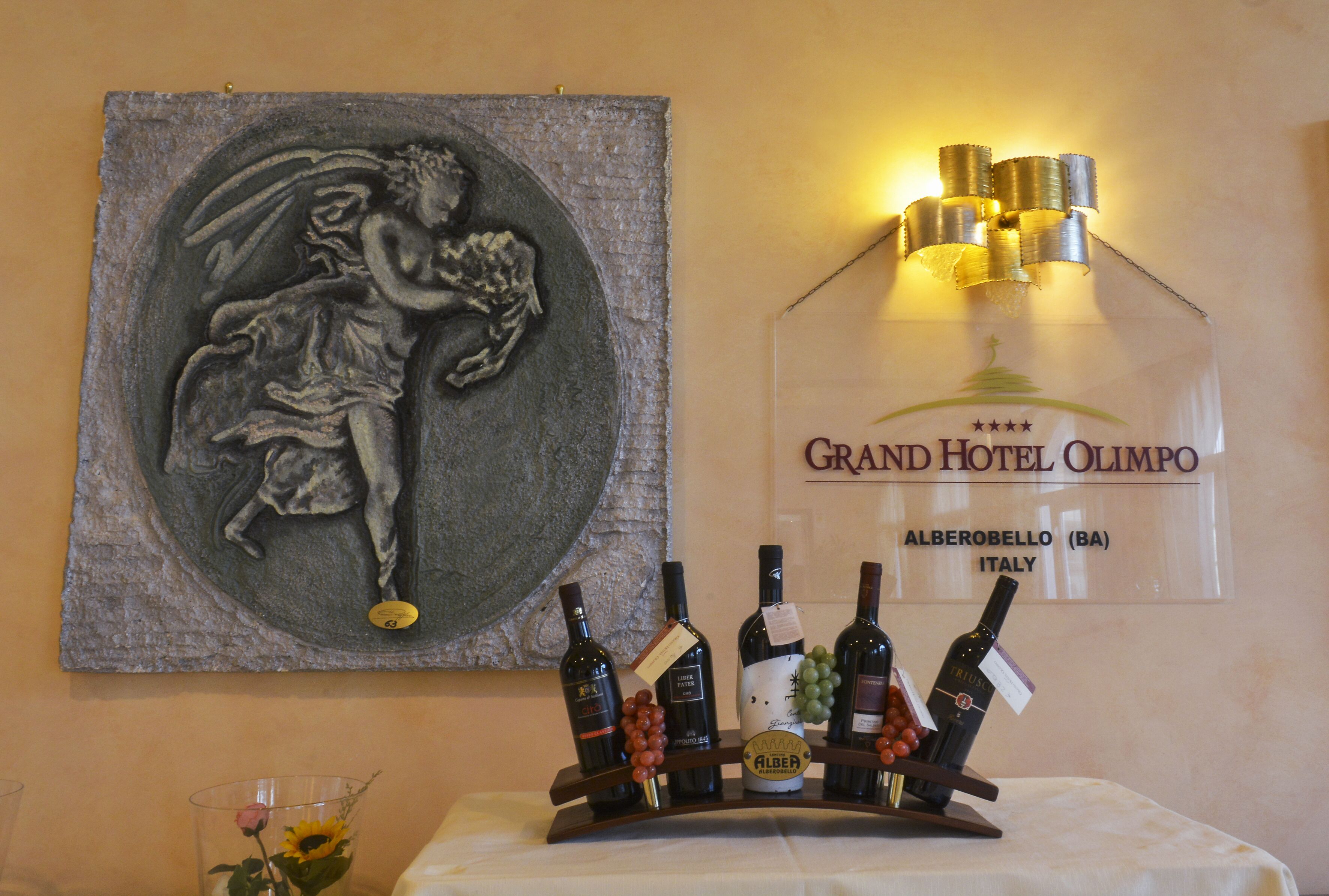 Exposição de vinhos com garrafas e um painel decorativo.