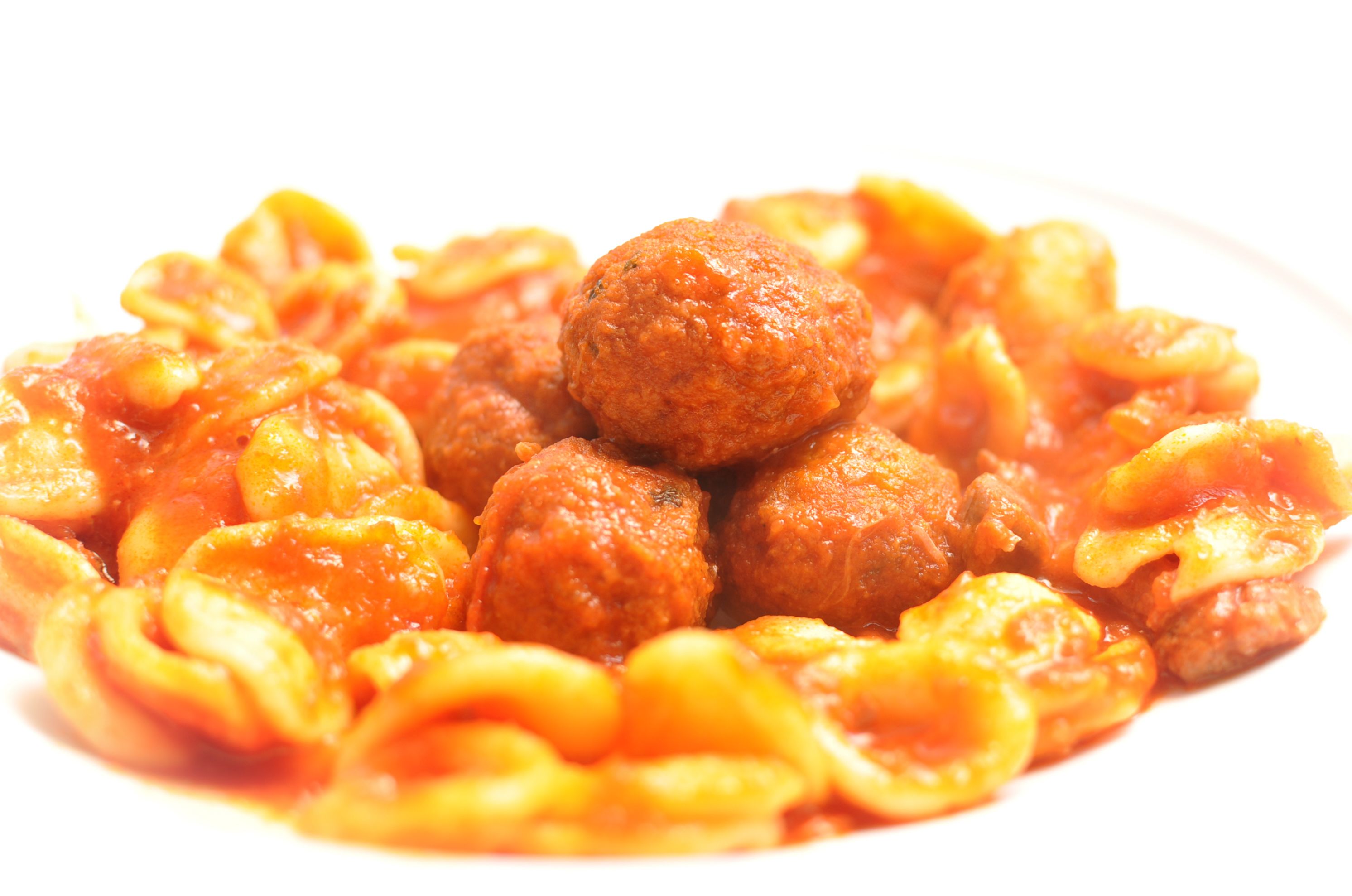 Un plato de pasta con albóndigas y salsa.
