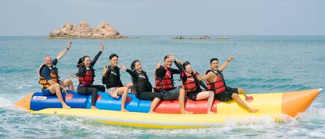 A group of people on a colorful inflatable raft in the ocean with a rocky island in the background.