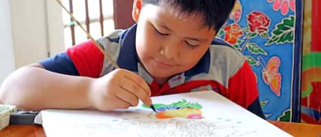 Un niño pintando sobre un papel con un fondo colorido.