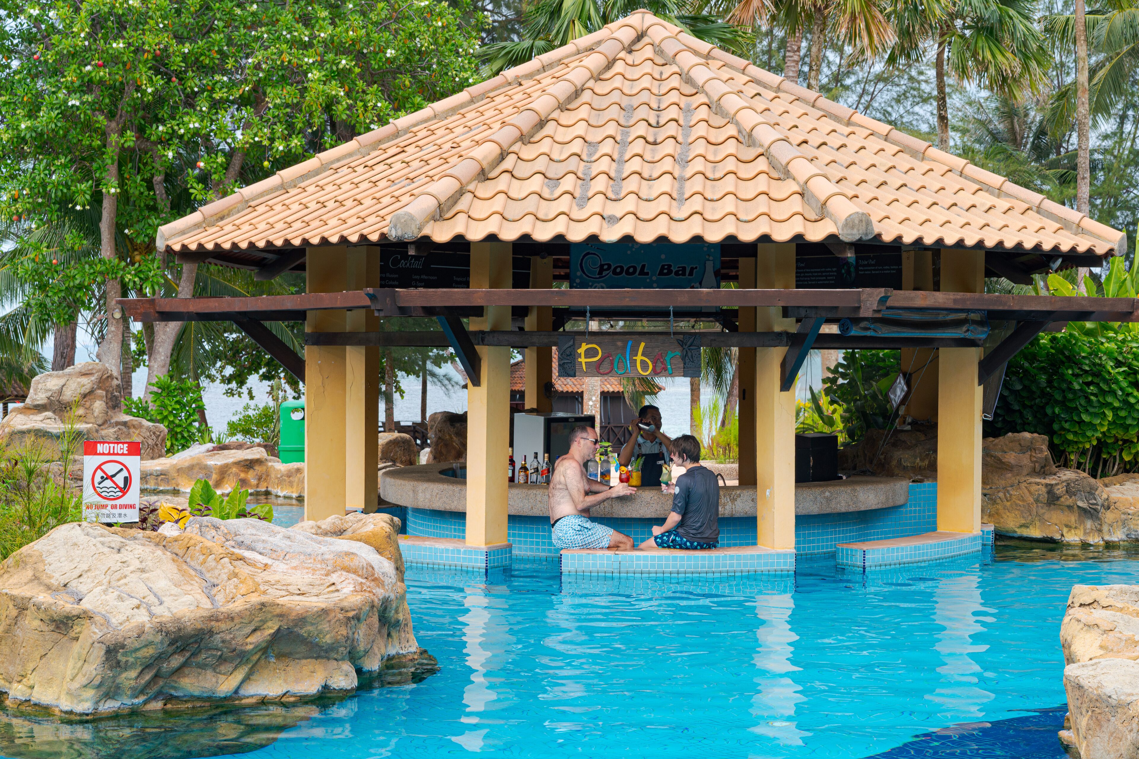 A poolside bar with a tiled roof and a sign reading "Pool Bar."