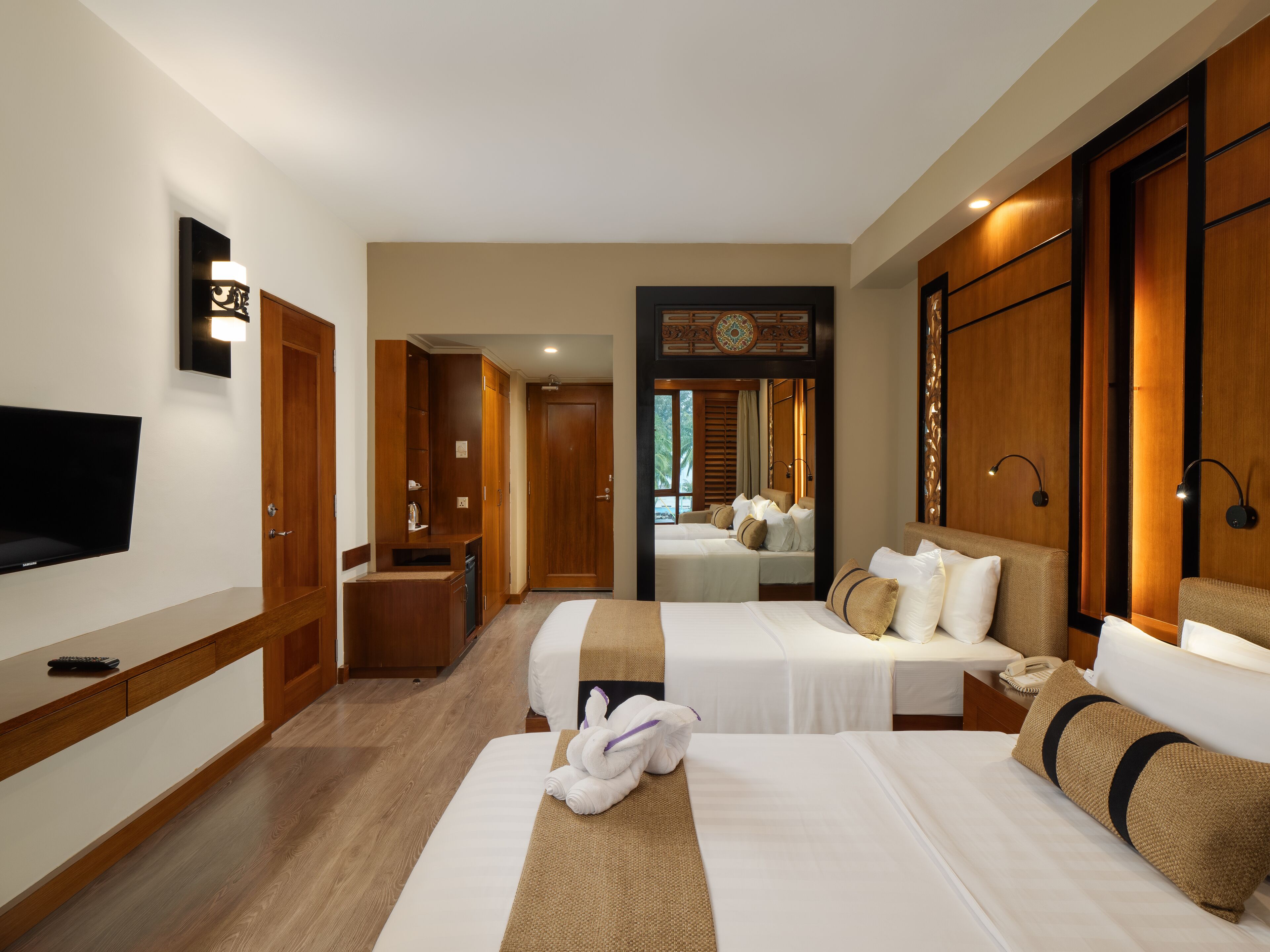 A hotel room with two beds, a TV, a desk, and a bathroom.