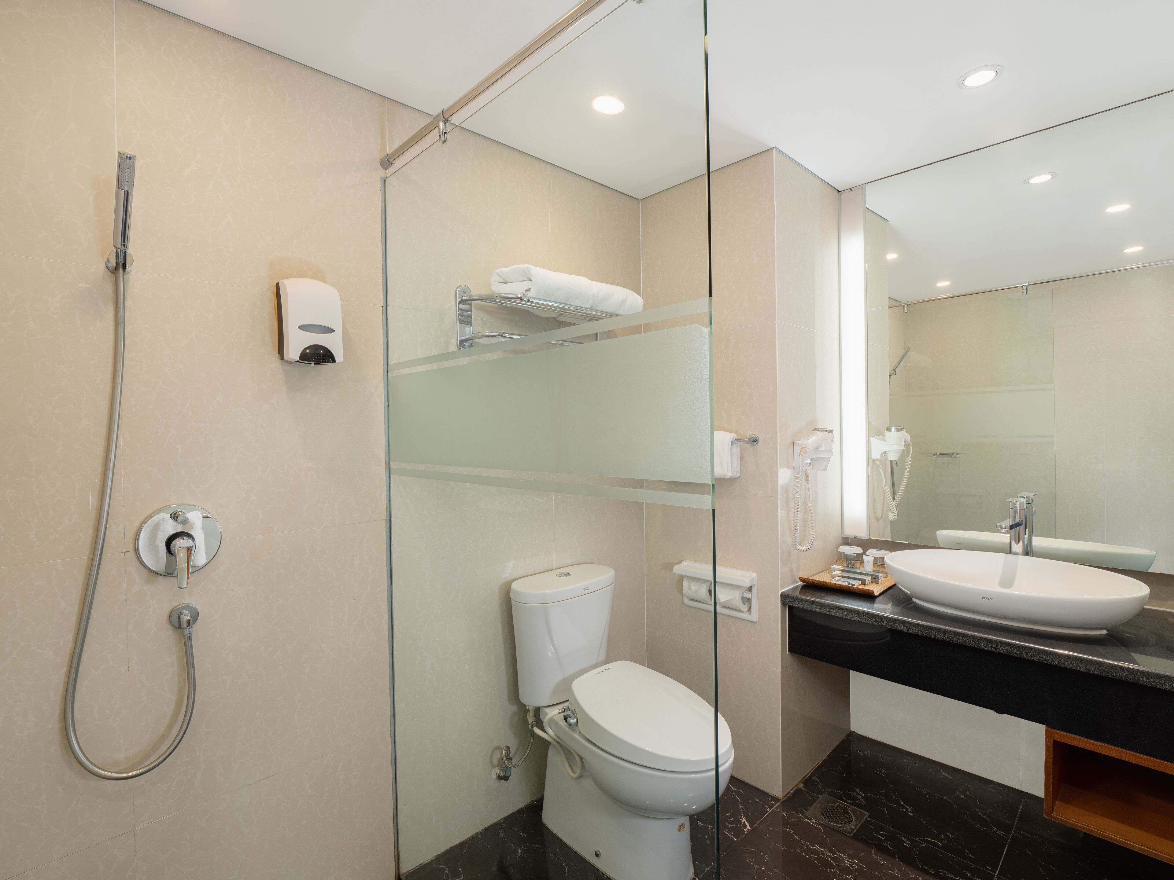 Une salle de bain moderne avec une douche à parois de verre, des toilettes, un lavabo et un miroir.