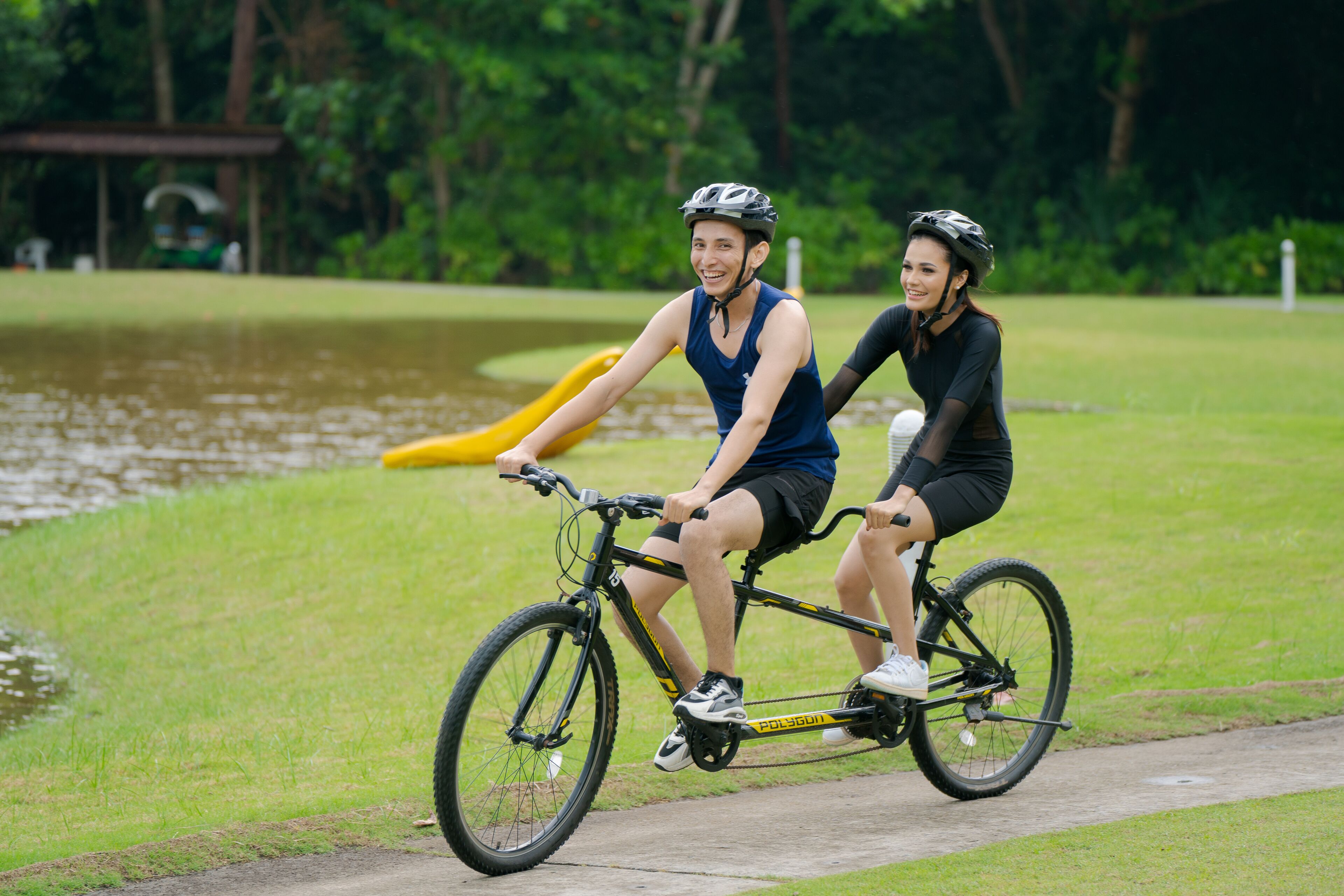 Two people riding a tandem bicycle on a path.