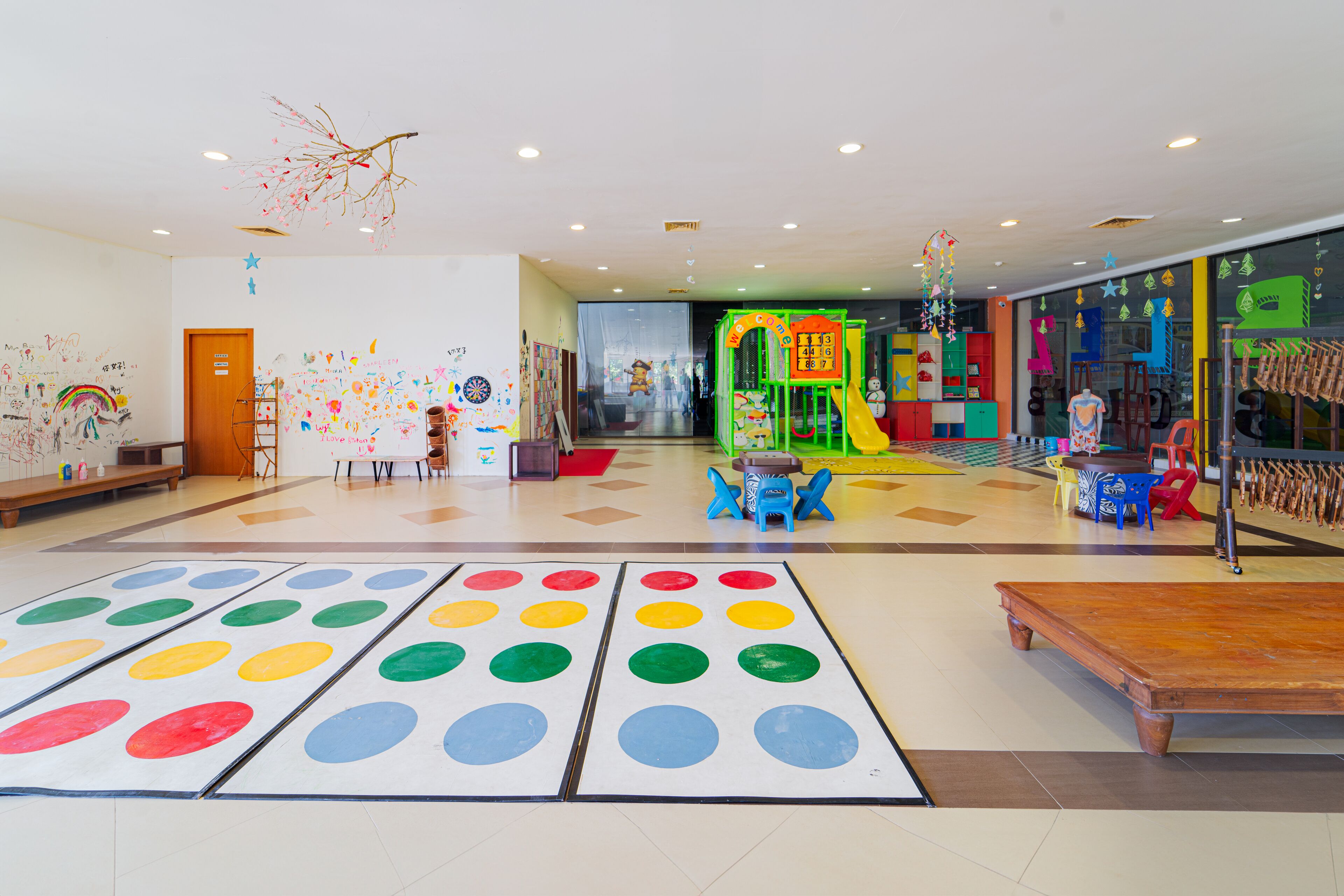 Zona infantil con estructuras de juego coloridas y un gran juego en el suelo.
