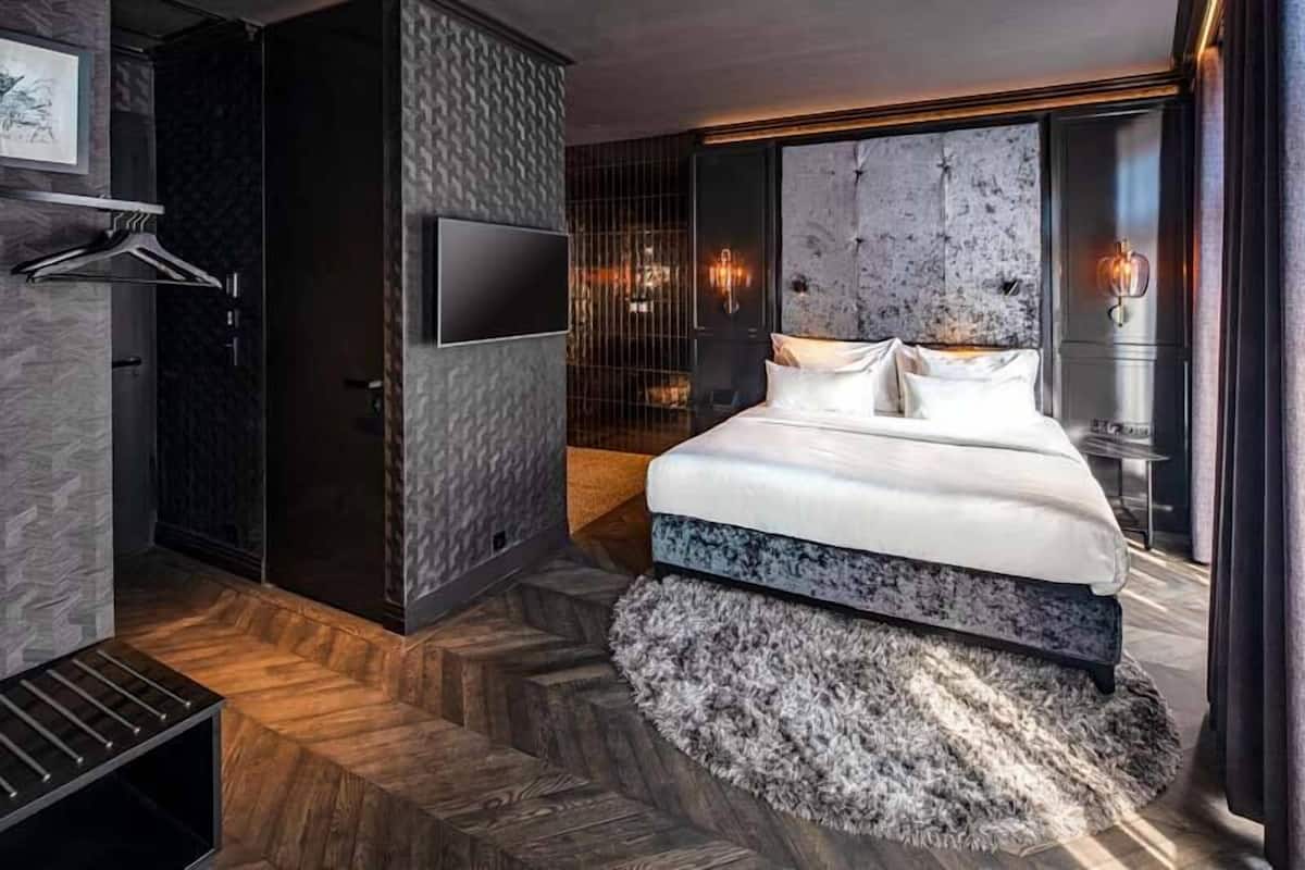 Una camera da letto moderna con un letto grande, una TV fissata al muro e un originale design delle pareti.