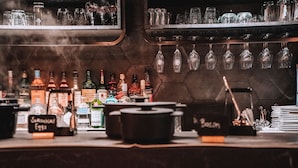 A bar area with various bottles and glasses, a chalkboard menu, and a pot on the counter. - The Highlander (Amsterdam)