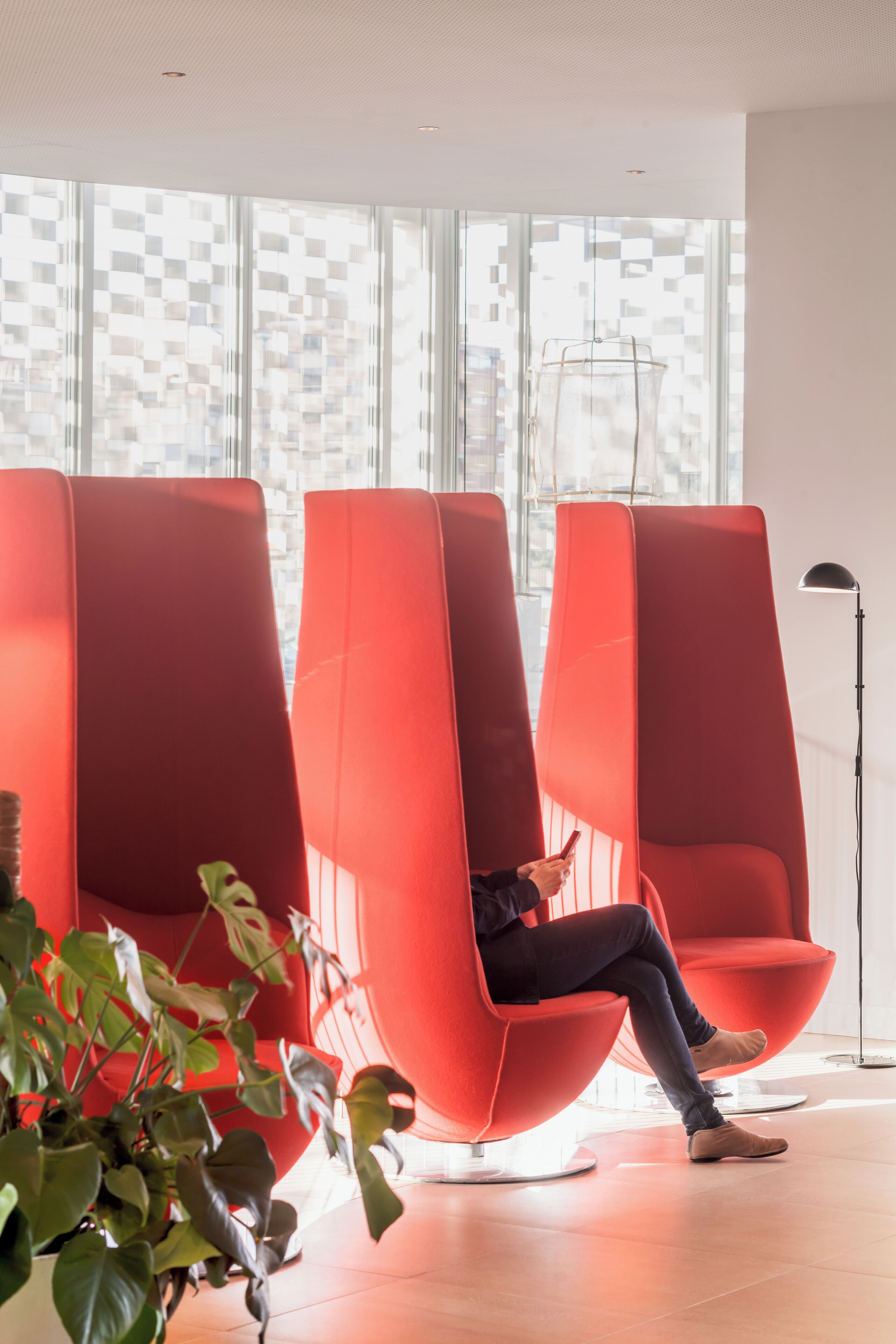 Un intérieur moderne avec des chaises rouges, une plante en pot et un lampadaire.