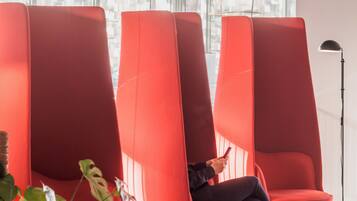 Un intérieur moderne avec des chaises rouges, une plante en pot et un lampadaire.