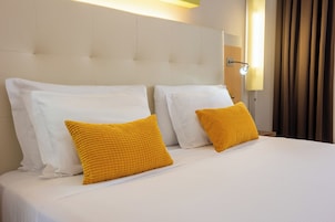Una camera d'albergo con un letto grande, due cuscini bianchi e due cuscini gialli.