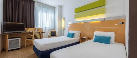 Une chambre d’hôtel avec deux lits, un bureau avec une télévision, un mini-réfrigérateur et une chaise.