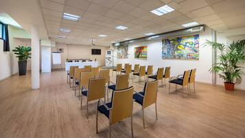 A conference room with rows of chairs, a whiteboard, and abstract paintings on the walls.