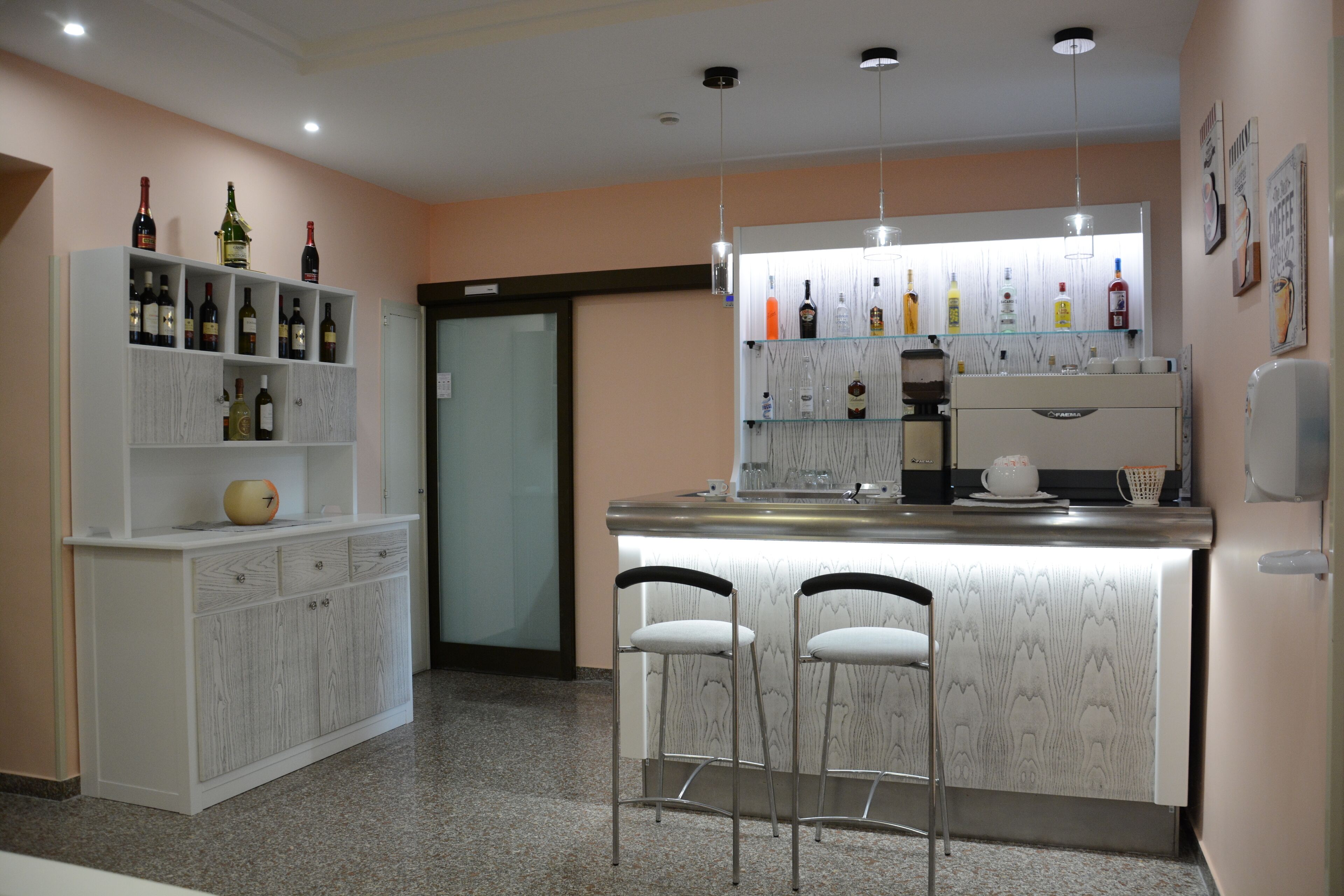 A modern kitchen with a bar area, featuring a wine rack, bar stools, and a coffee machine.