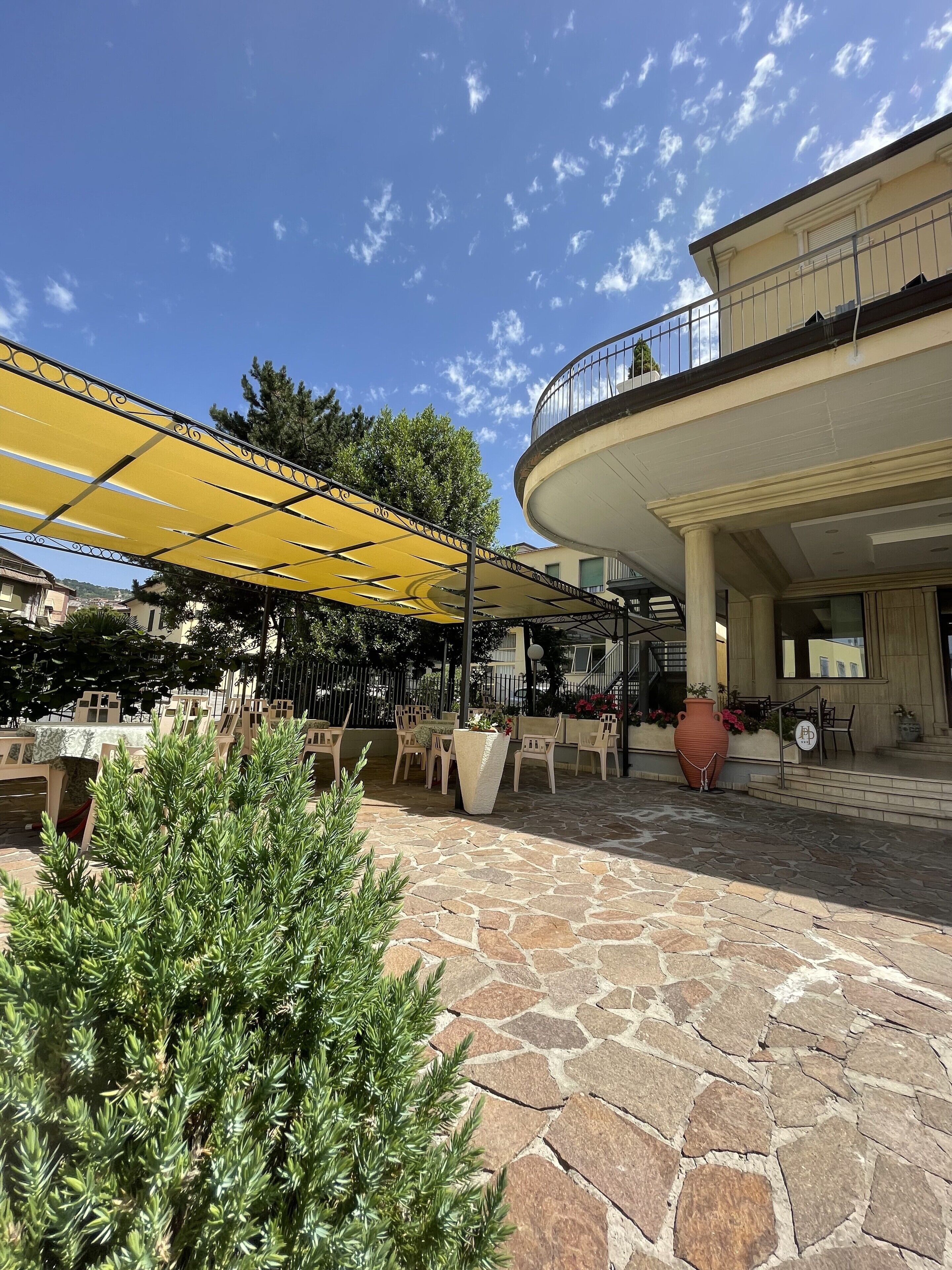An outdoor patio area with stone flooring, yellow canopies, and outdoor seating.