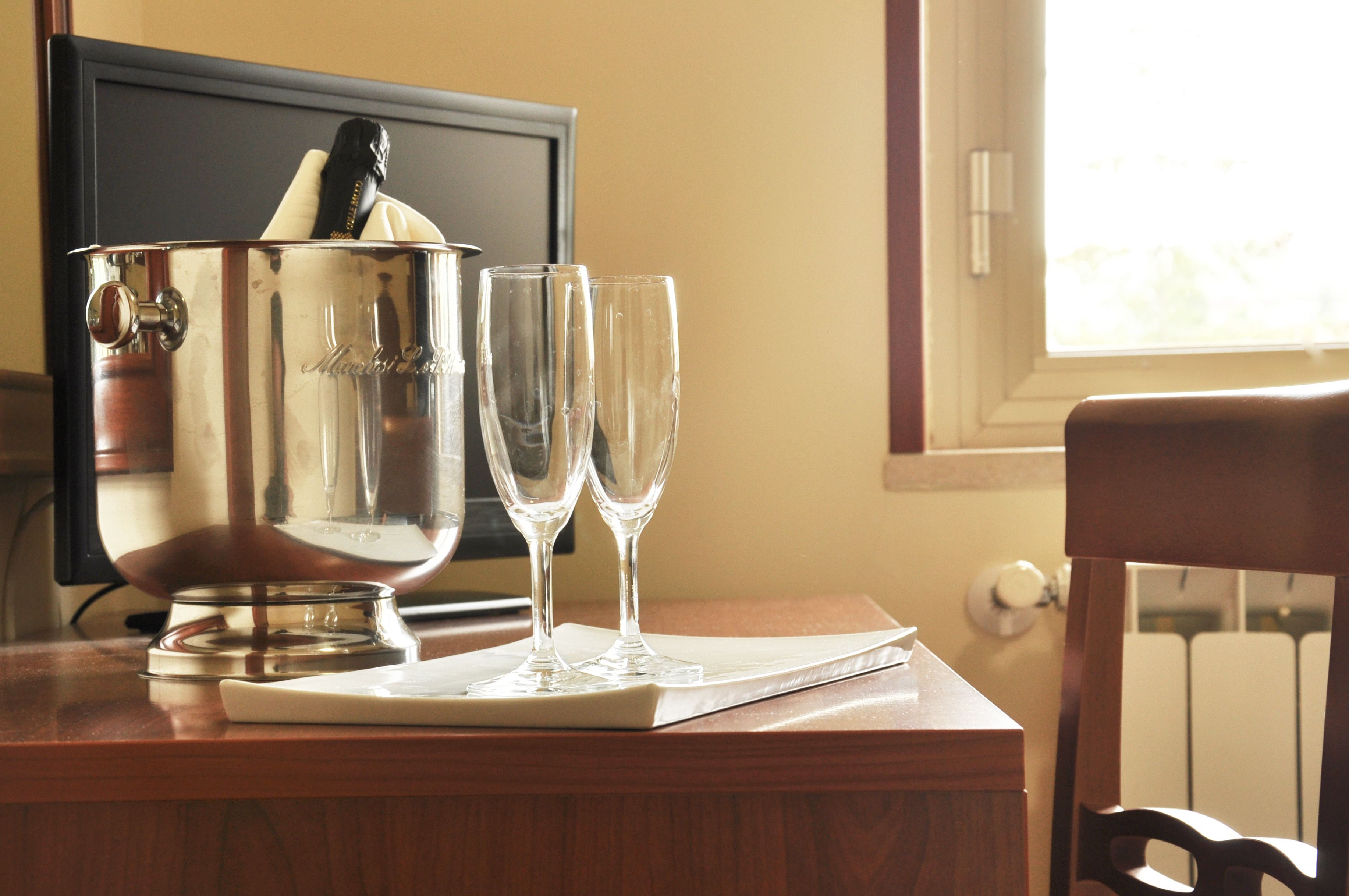 A wooden table with a silver bucket and two empty glasses on a white napkin.