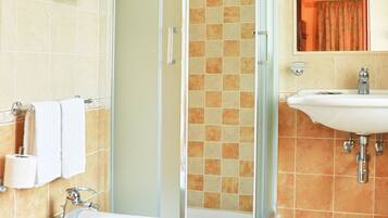 Un baño con cabina de ducha de vidrio, lavabo y dos inodoros.