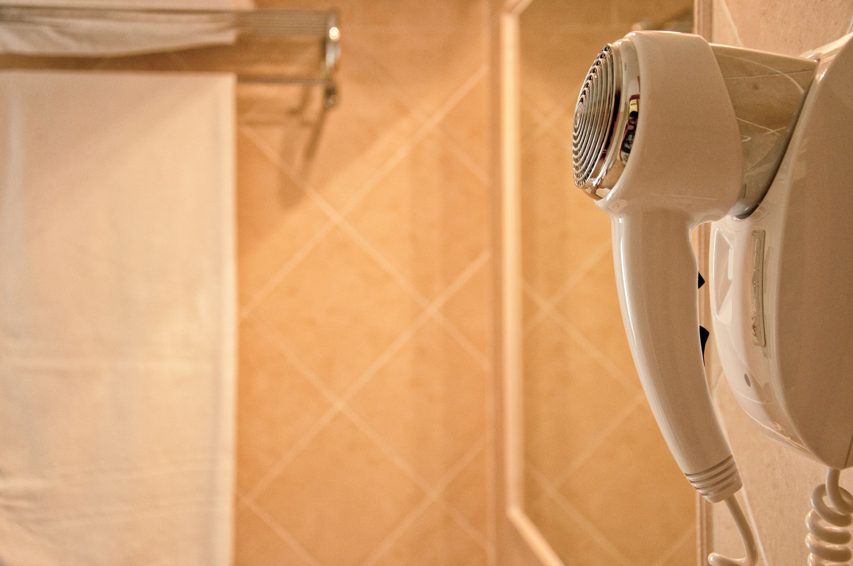 A hair dryer mounted on a wall in a bathroom with a patterned tile design.