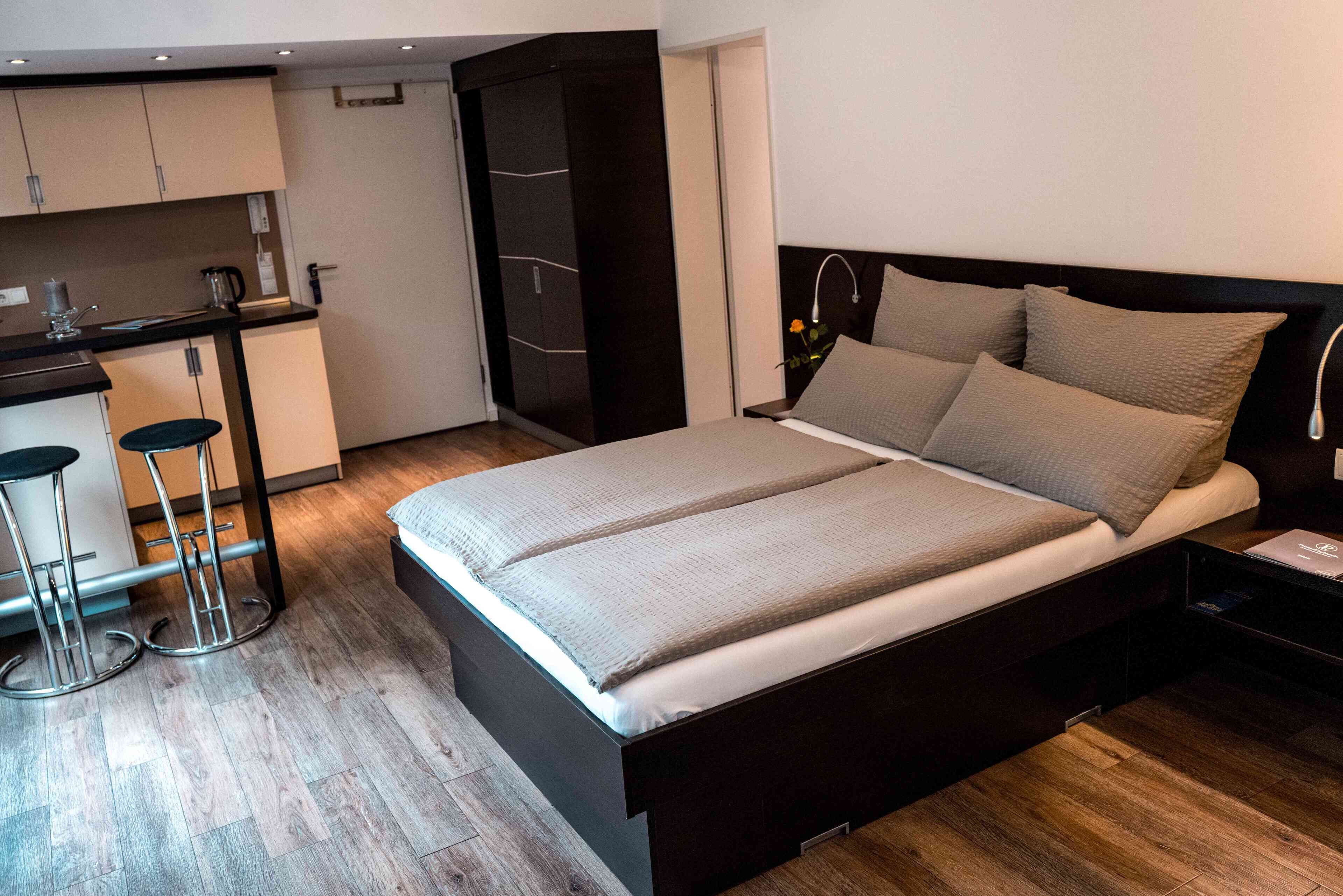 Ein modernes Schlafzimmer mit einem großen Bett, einer kleinen Küchenzeile und einem separaten Badezimmerbereich.