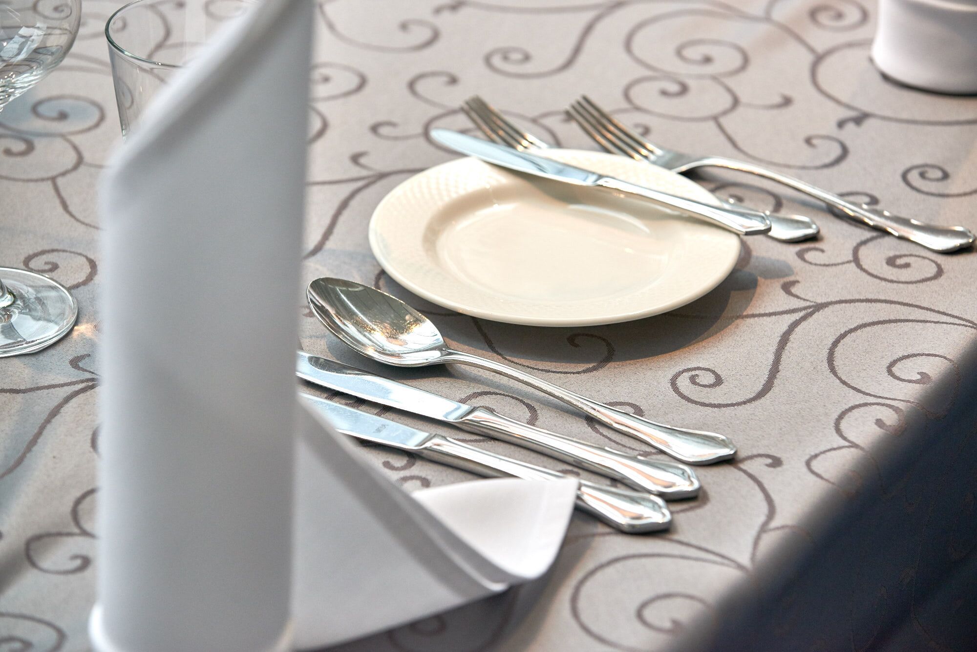 Una mesa dispuesta con un plato, un tenedor, un cuchillo y una cuchara.